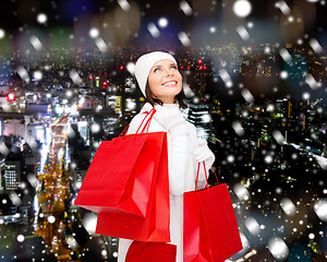 Image showing smiling young woman with red shopping bags