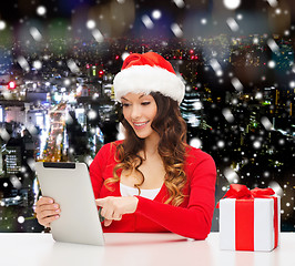 Image showing smiling woman in santa hat with gift and tablet pc