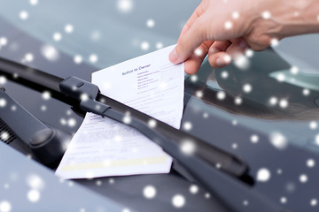 Image showing close up of male hand with parking ticket on car