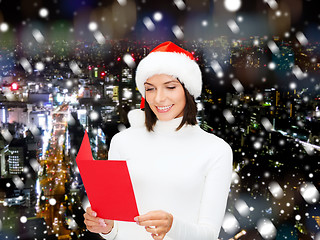 Image showing smiling woman in santa hat with greeting card