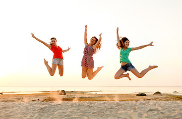 Image showing smiling teen girls jumping on beach