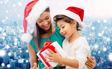 Image showing happy mother and girl in santa hats with gift box