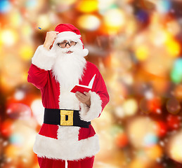 Image showing man in costume of santa claus with notepad