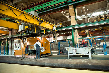 Image showing Workers operate machine on filling of plates