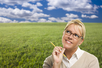 Image showing Contemplative Woman in Grass Field Looking Up and Over