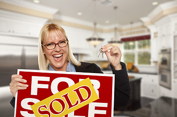 Image showing Young Woman Holding Sold Sign and Keys Inside New Kitchen