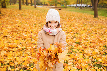 Image showing smiling little girl with autumn leaves in park