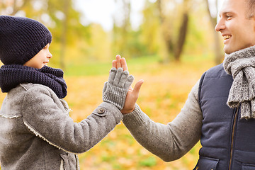 Image showing happy father and son making high five in park