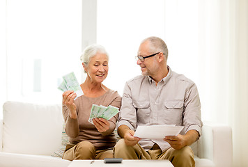 Image showing senior couple with money and calculator at home