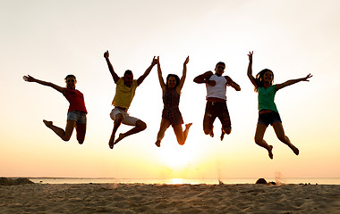 Image showing smiling friends dancing and jumping on beach