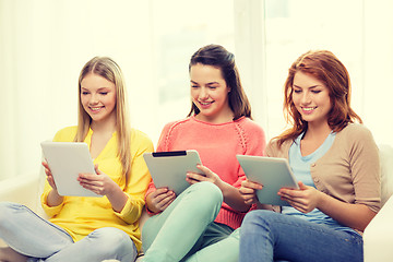 Image showing three smiling teenage girls with tablet pc at home