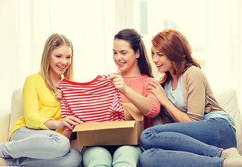 Image showing smiling teenage girls opening cardboard box