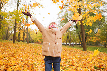 Image showing smiling little girl with autumn leaves in park