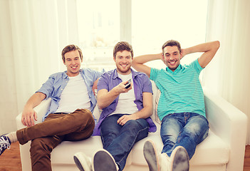 Image showing smiling friends with remote control at home