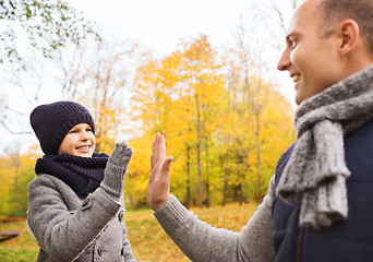 Image showing happy father and son making high five in park