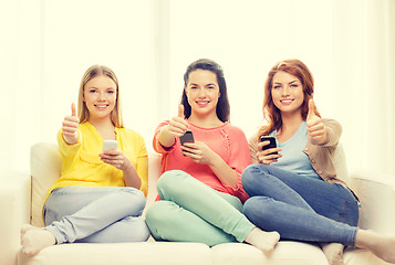 Image showing smiling teenage girls with smartphones at home