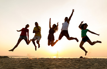 Image showing smiling friends dancing and jumping on beach