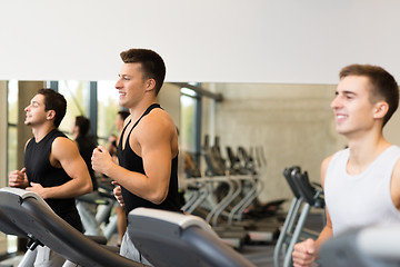 Image showing smiling men exercising on treadmill in gym