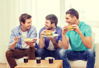 Image showing smiling friends with soda and hamburgers at home