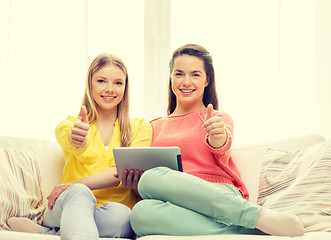 Image showing two smiling teenage girls with tablet pc at home