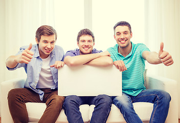 Image showing smiling male friends holding white blank board