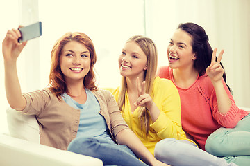 Image showing smiling teenage girls with smartphone at home