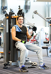 Image showing smiling man exercising on gym machine