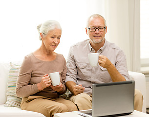 Image showing happy senior couple with laptop and cups at home