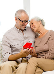 Image showing happy senior couple with red gift box at home