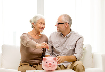 Image showing senior couple with money and piggy bank at home