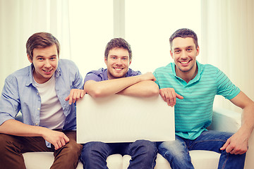 Image showing smiling male friends holding white blank board