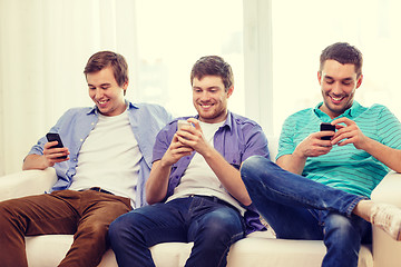 Image showing smiling friends with smartphones at home