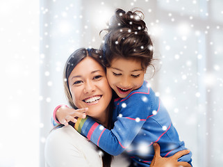 Image showing smiling little girl and mother hugging indoors