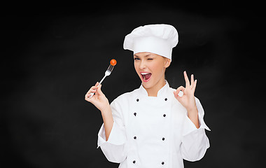 Image showing smiling female chef with fork and tomato