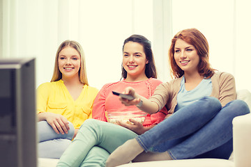 Image showing three smiling teenage girl watching tv at home