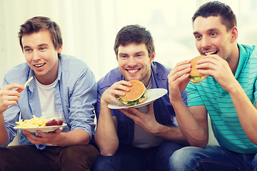 Image showing smiling friends with soda and hamburgers at home