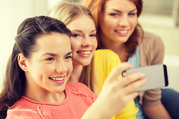 Image showing smiling teenage girls with smartphone at home