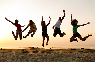 Image showing smiling friends dancing and jumping on beach