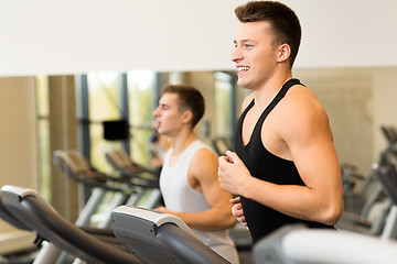 Image showing smiling men exercising on treadmill in gym