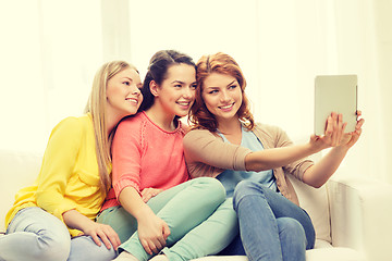 Image showing three smiling teenage girls with tablet pc at home