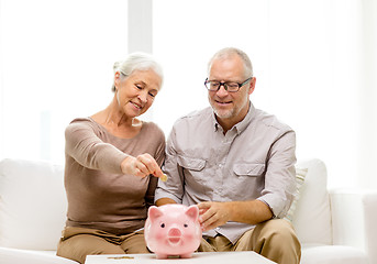 Image showing senior couple with money and piggy bank at home