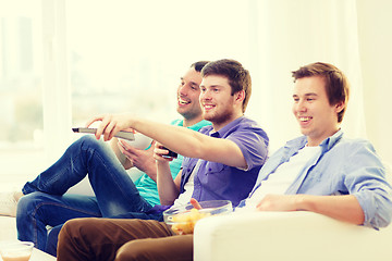 Image showing smiling friends with remote control at home