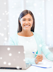 Image showing smiling young woman with laptop and notebook