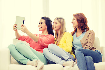 Image showing three smiling teenage girls with tablet pc at home