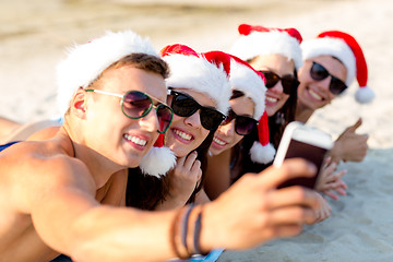 Image showing group of friends in santa hats with smartphone