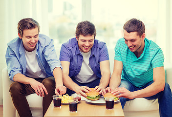 Image showing smiling friends with soda and hamburgers at home