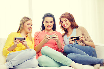 Image showing smiling teenage girls with smartphones at home