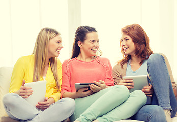 Image showing three smiling teenage girls with tablet pc at home