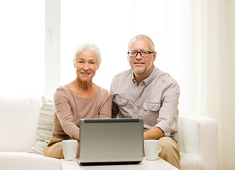 Image showing happy senior couple with laptop and cups at home