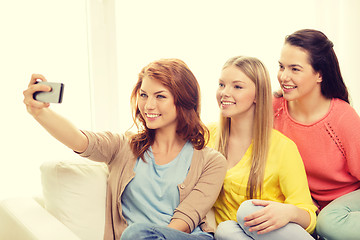 Image showing smiling teenage girls with smartphone at home